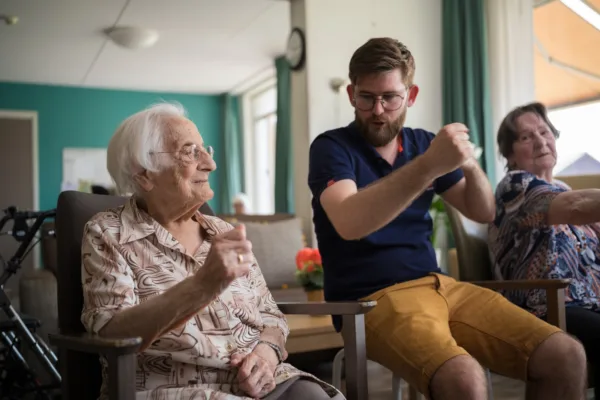 Medewerker en cliënt tijdens oefening met handen - Ergotherapie
