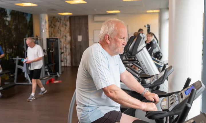 Cliënt aan het fietsen in de fitness - Seniorenfitness