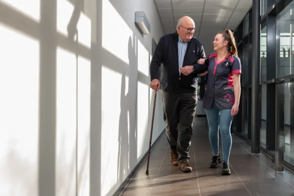 Medewerker en cliënt lopen samen door de gang - Tijdelijke Zorg
