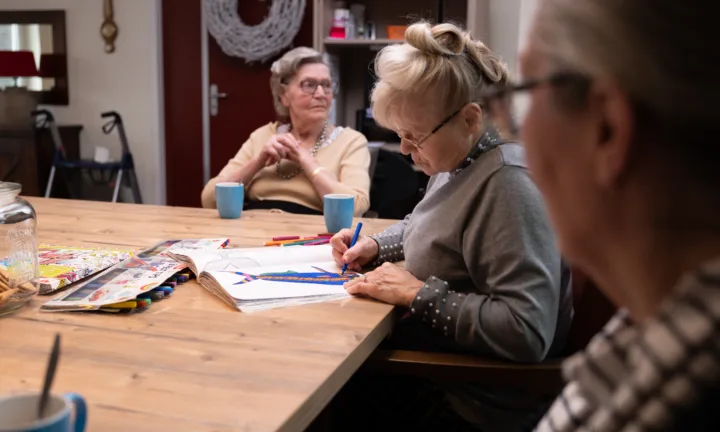 Cliënt is aan het tekenen aan tafel - Dementie