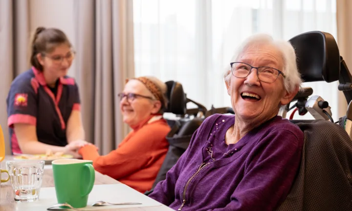 Bewoner kijkt lachend aan tafel - Somatiek