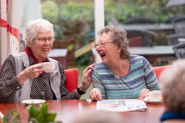 Bewoners samen lachend aan tafel - Wonen met zorg