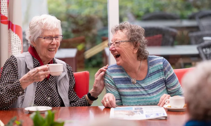 Bewoners samen lachend aan tafel - Wonen met zorg